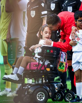 Rnaldo leva menina de cadeira de rodas para o relvado.