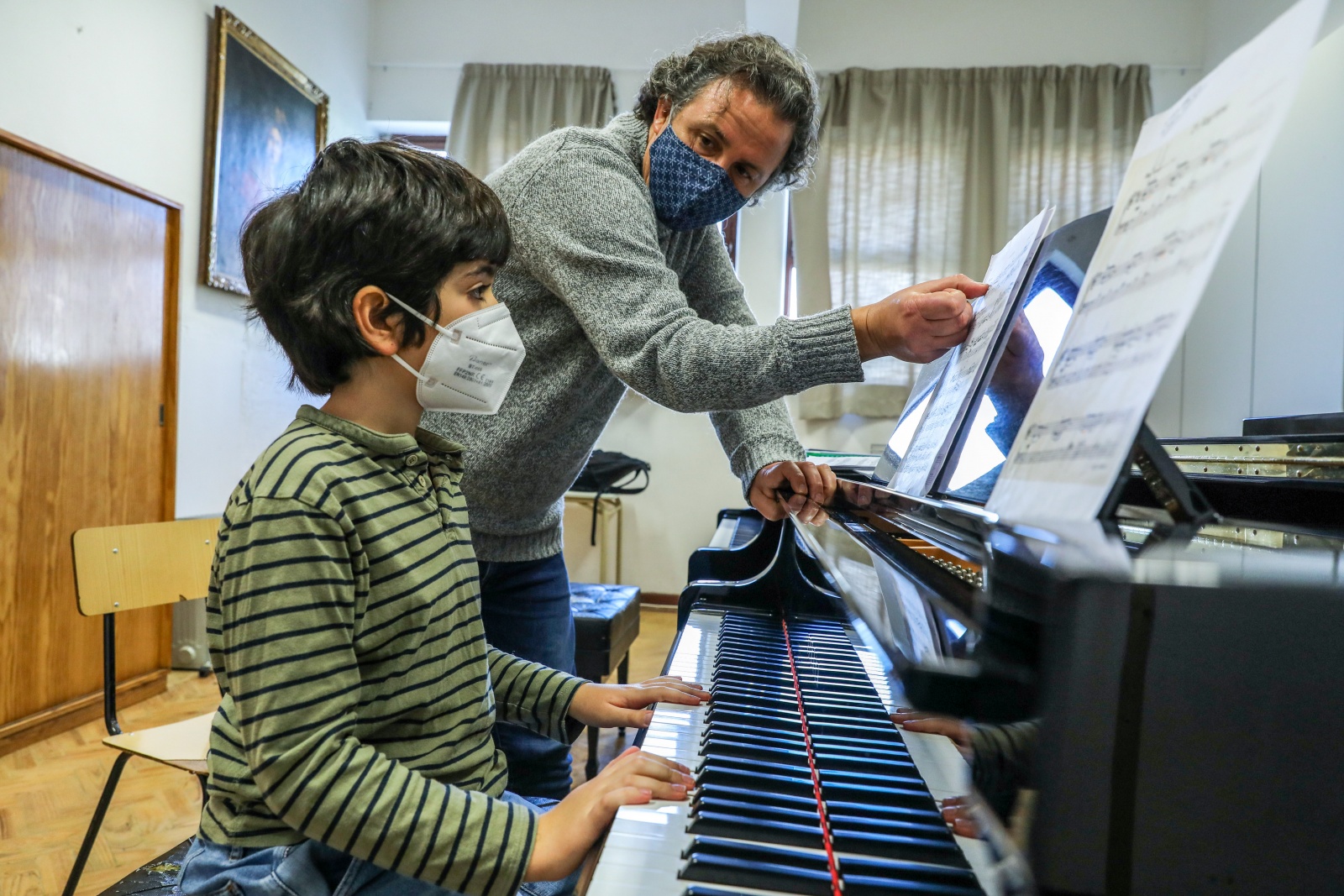 Professora ensinando seu aluno a tocar piano e gravar aula online