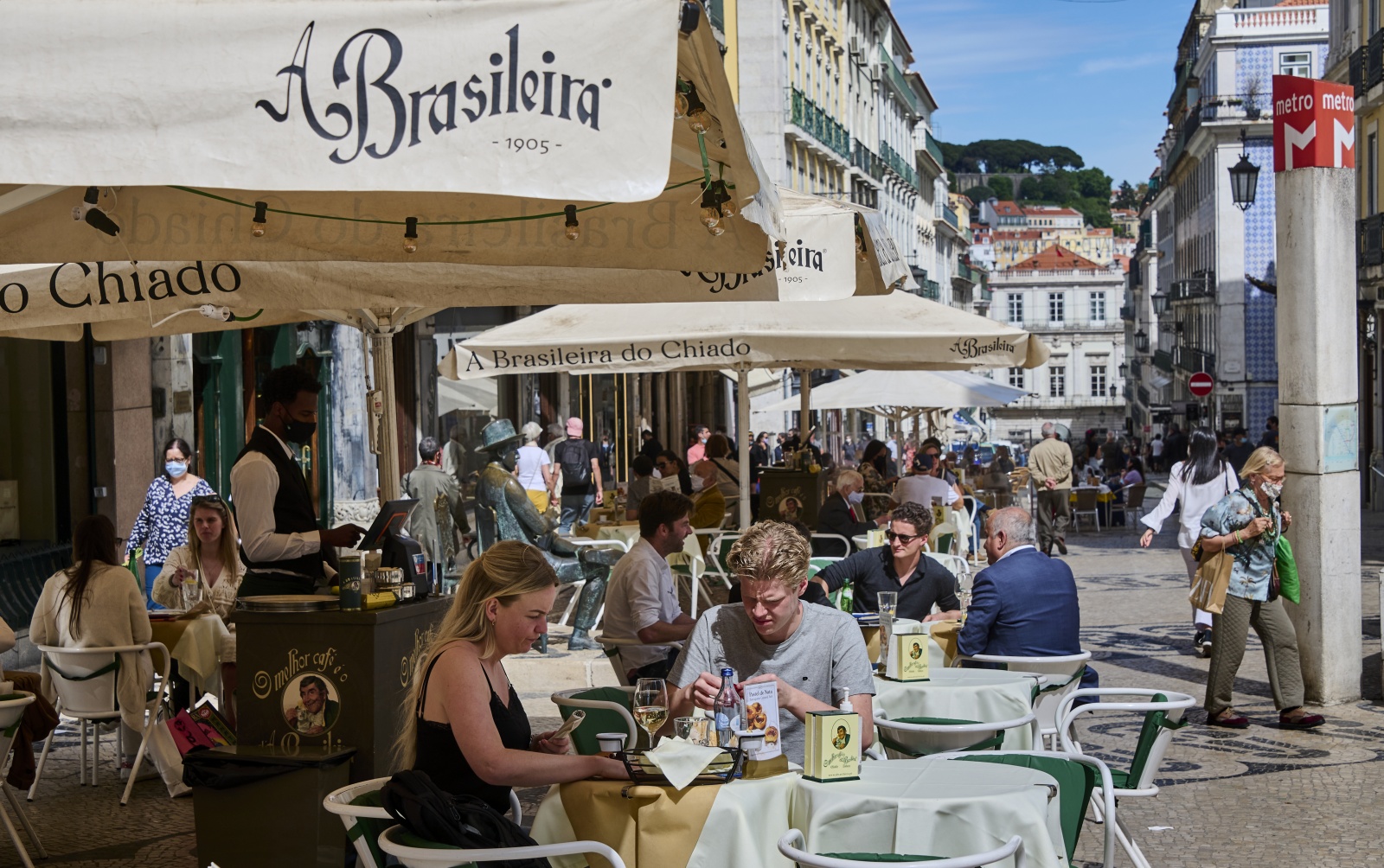 LISBON, PORTUGAL - APRIL 19: Patrons sit at sidewalk tables of A Brasileira Cafe in Rua Garrett on the first day of deconfinement's third phase with shops reopening with limitations and restaurants allowed to serve patrons indoors during the COVID-19 Coronavirus pandemic on April 19, 2021 in Lisbon, Portugal. According to updated data from the General Direction of Health (DGS) Portugal confirmed a total of 831,221 infections and 16,946 deaths since the beginning of the pandemic. The government has relaxed confinement and renewed the country's state of emergency until April 30. (Photo by Horacio Villalobos#Corbis/Corbis via Getty Images)