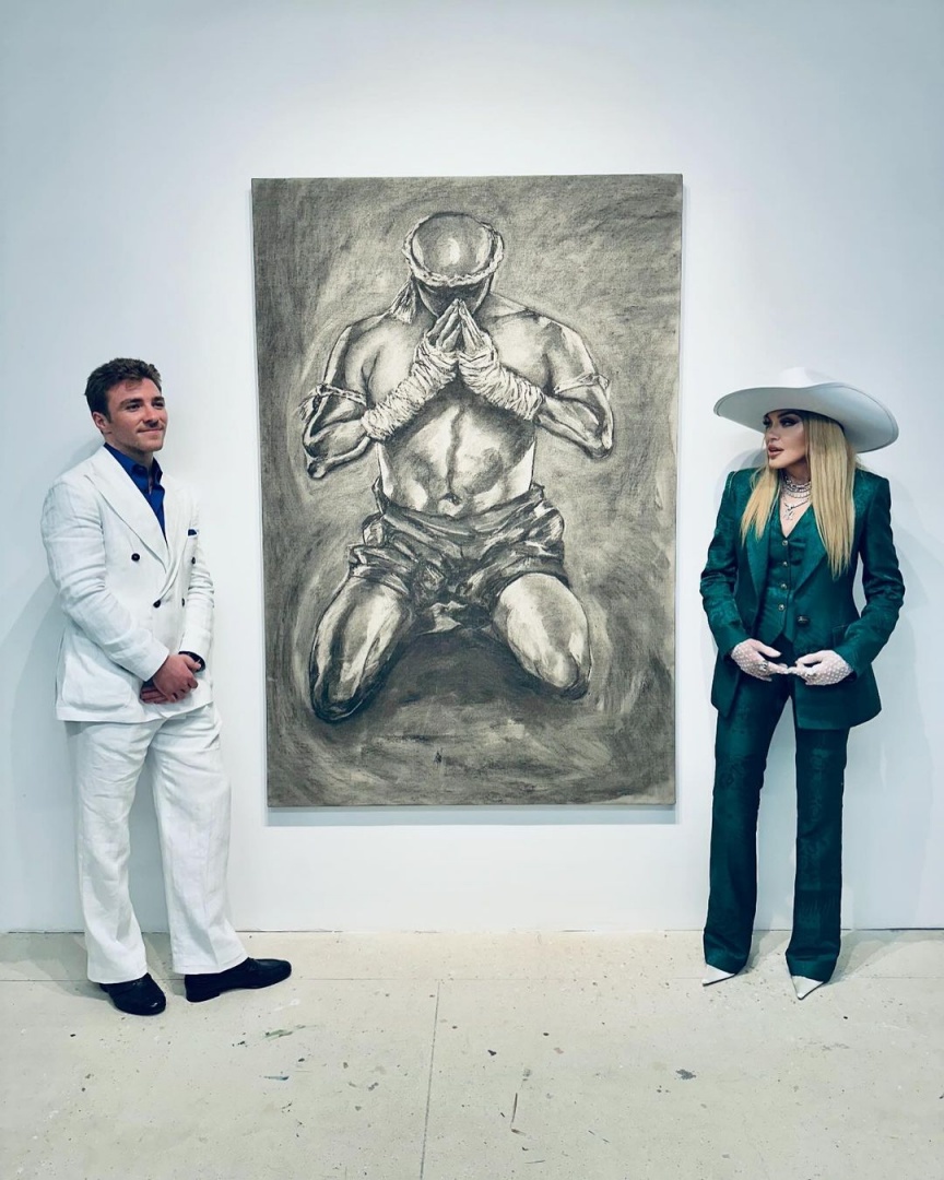 Madonna posa com o filho perto de uma das suas pinturas

